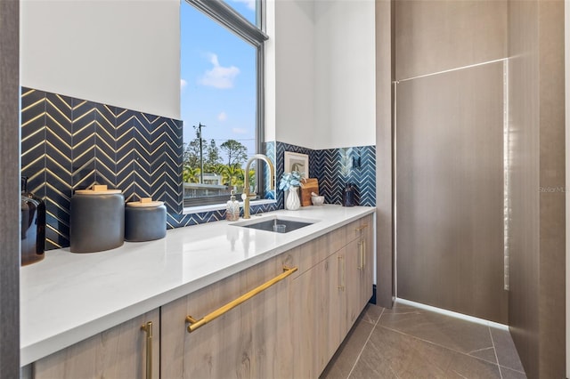 kitchen featuring light brown cabinetry, dark tile patterned flooring, and sink