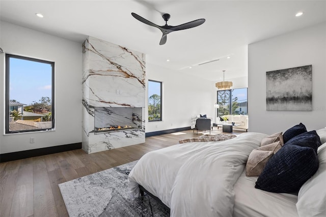 bedroom with ceiling fan, a fireplace, and dark hardwood / wood-style flooring
