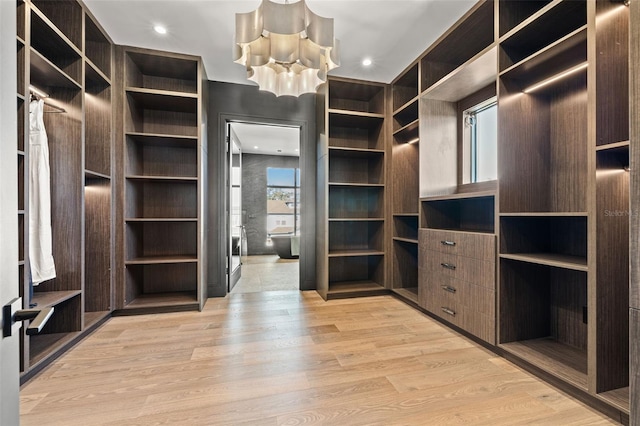 spacious closet featuring a notable chandelier and light wood-type flooring