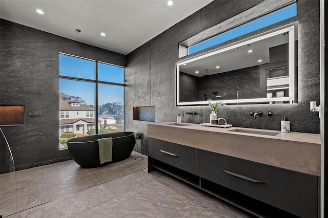 bathroom with vanity, a bathtub, and tile walls