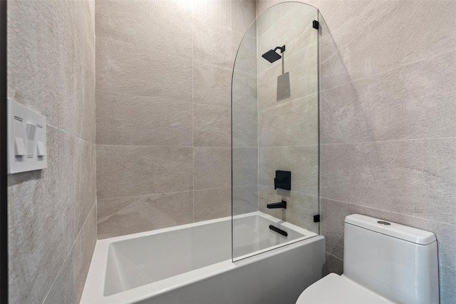 bathroom with shower / washtub combination, toilet, and tile walls