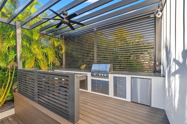 wooden terrace with ceiling fan, area for grilling, a pergola, and exterior kitchen