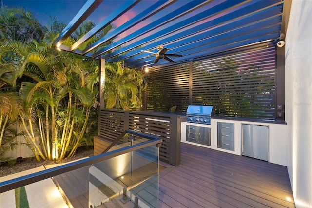 wooden terrace featuring ceiling fan, area for grilling, a pergola, and exterior kitchen