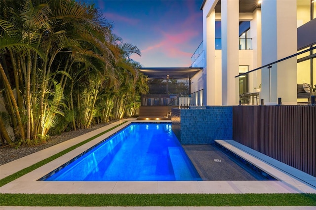 pool at dusk featuring ceiling fan
