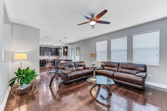 living room with dark wood-type flooring and ceiling fan