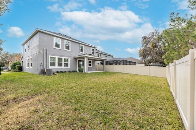 rear view of property with central AC unit, a yard, and a patio