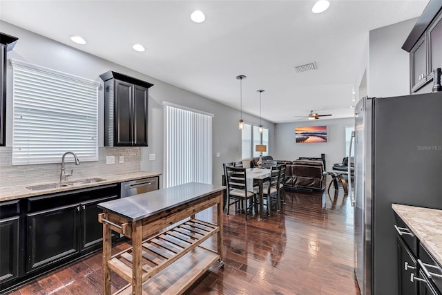 kitchen featuring sink, decorative light fixtures, appliances with stainless steel finishes, dark hardwood / wood-style flooring, and backsplash