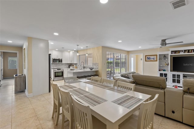 dining area featuring light tile patterned flooring, ceiling fan, and sink