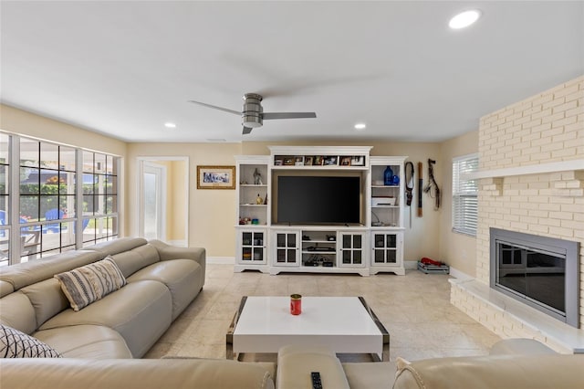 tiled living room featuring a brick fireplace, a healthy amount of sunlight, and ceiling fan