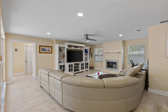 tiled living room featuring a brick fireplace and ceiling fan