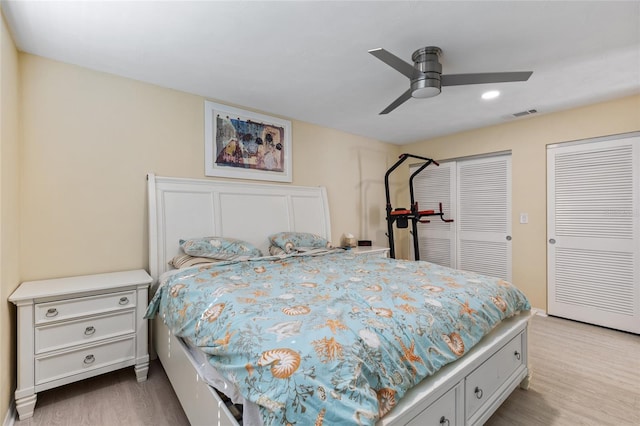 bedroom featuring ceiling fan, light hardwood / wood-style floors, and two closets