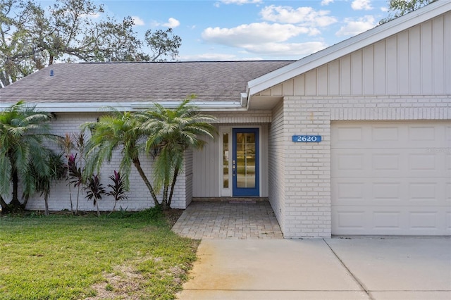 entrance to property featuring a garage and a lawn