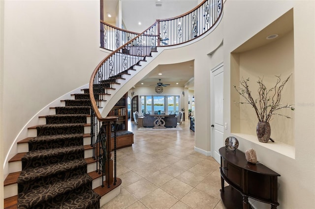 tiled foyer with ceiling fan and a high ceiling