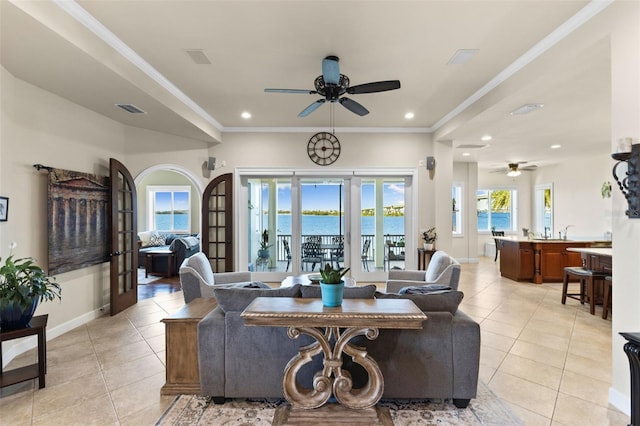 tiled living room with crown molding, a water view, ceiling fan, and french doors