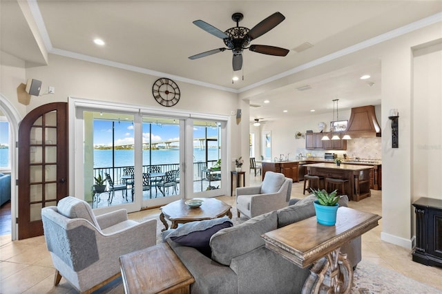 living room with a water view, ceiling fan, ornamental molding, and light tile patterned floors