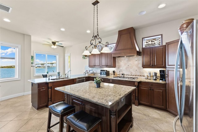 kitchen featuring a kitchen island, premium range hood, appliances with stainless steel finishes, and kitchen peninsula