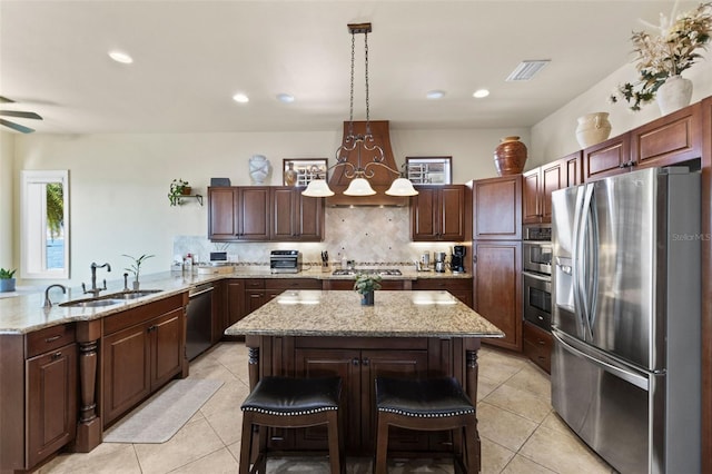 kitchen with pendant lighting, sink, appliances with stainless steel finishes, backsplash, and a kitchen breakfast bar