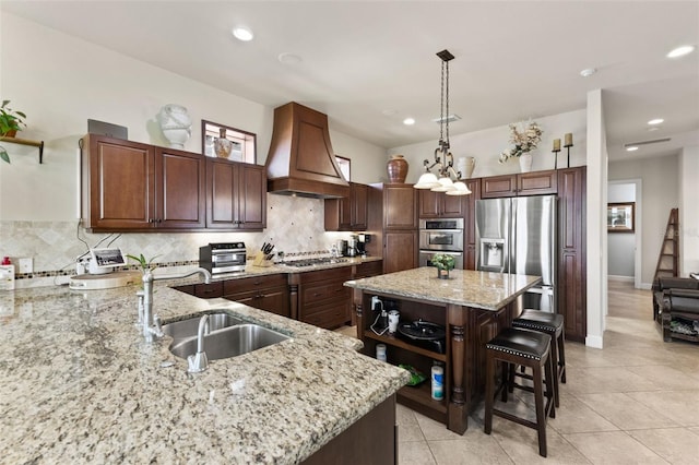 kitchen featuring a kitchen island, appliances with stainless steel finishes, sink, hanging light fixtures, and custom range hood