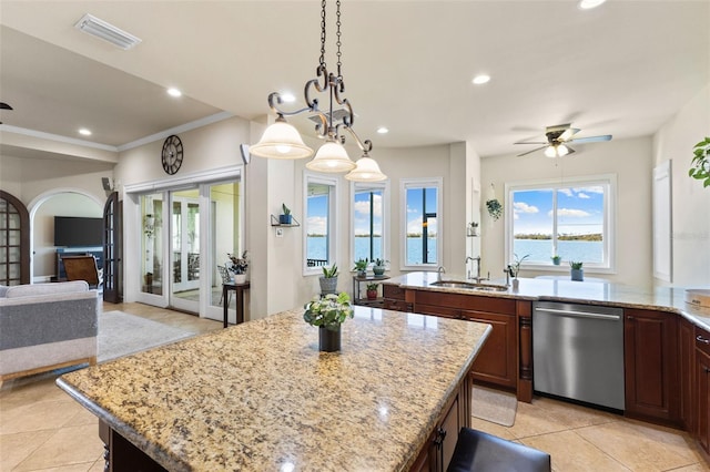 kitchen with a water view, dishwasher, light stone counters, and a kitchen island