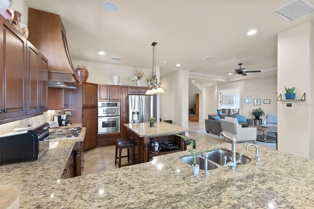 kitchen featuring appliances with stainless steel finishes, sink, a breakfast bar area, hanging light fixtures, and light stone counters