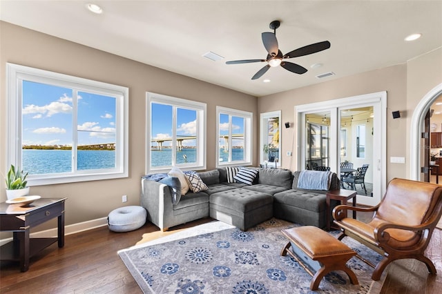 living room with a water view, ceiling fan, and dark wood-type flooring