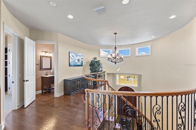 staircase featuring sink, hardwood / wood-style flooring, and a notable chandelier