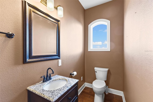 bathroom with hardwood / wood-style flooring, vanity, and toilet