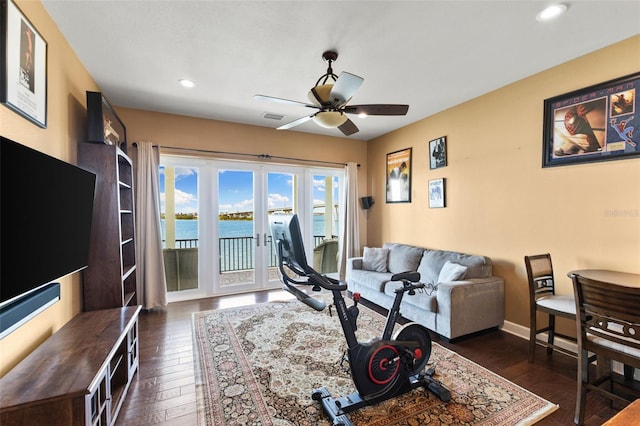 living room featuring french doors, dark hardwood / wood-style floors, ceiling fan, and a water view