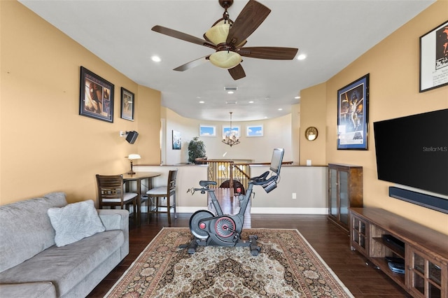 living room featuring dark wood-type flooring and ceiling fan with notable chandelier