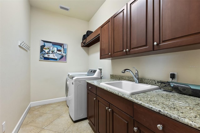 washroom featuring sink, light tile patterned floors, washing machine and dryer, and cabinets