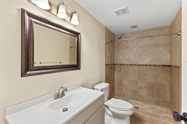 bathroom with vanity, toilet, and a tile shower