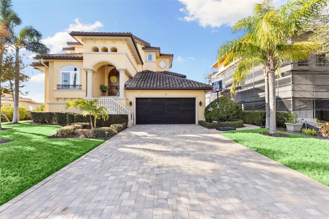 mediterranean / spanish home with a garage and a front lawn