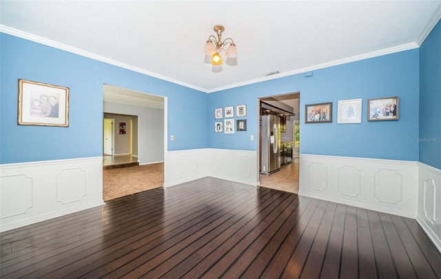 spare room with ornamental molding, hardwood / wood-style floors, and a chandelier