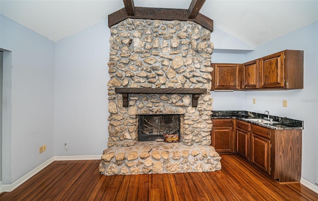 kitchen featuring a stone fireplace, sink, lofted ceiling, and dark hardwood / wood-style floors