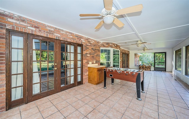 playroom with brick wall, light tile patterned floors, and french doors