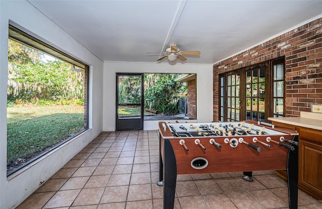 rec room with brick wall, plenty of natural light, and light tile patterned floors