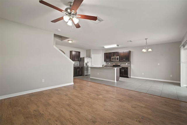 unfurnished living room with ceiling fan with notable chandelier and light hardwood / wood-style flooring