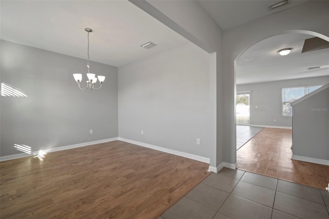 tiled empty room with an inviting chandelier