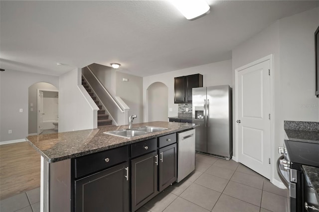 kitchen with sink, light tile patterned flooring, stainless steel appliances, and a center island with sink