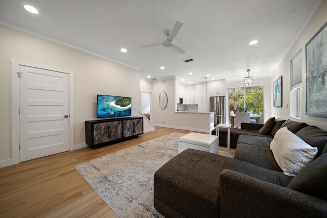 living room featuring light hardwood / wood-style flooring, ornamental molding, and ceiling fan