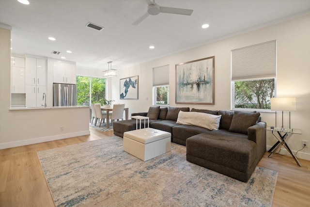 living room featuring sink, ceiling fan, and light wood-type flooring