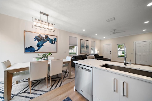 kitchen with dishwasher, plenty of natural light, light stone counters, and decorative light fixtures