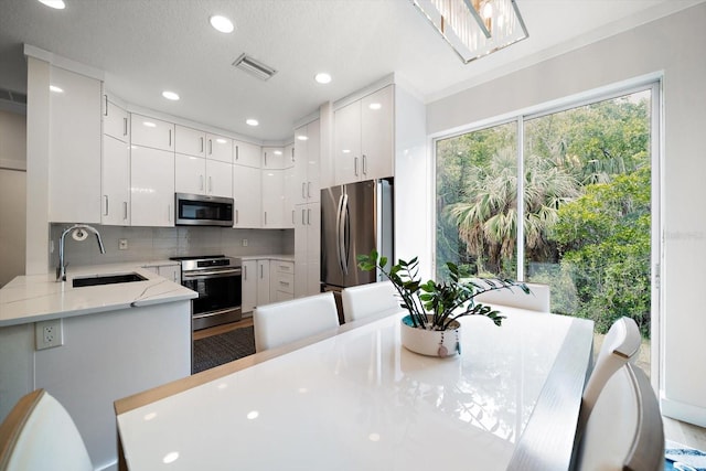 kitchen featuring sink, kitchen peninsula, white cabinets, and appliances with stainless steel finishes