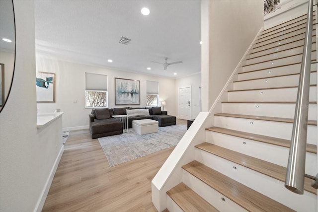 stairs with crown molding, wood-type flooring, and ceiling fan