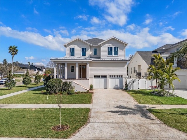 view of front of house featuring driveway, a residential view, metal roof, covered porch, and a front yard