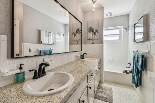 bathroom featuring tile walls, vanity, and bathtub / shower combination