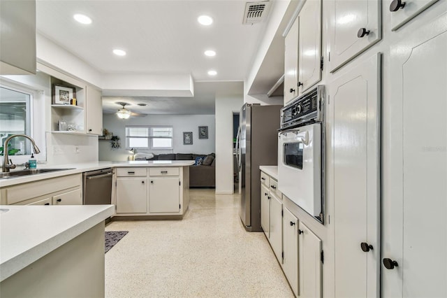 kitchen with sink, white cabinets, ceiling fan, kitchen peninsula, and stainless steel appliances