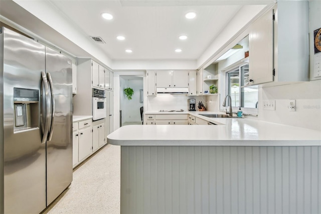 kitchen with sink, white appliances, kitchen peninsula, and white cabinets