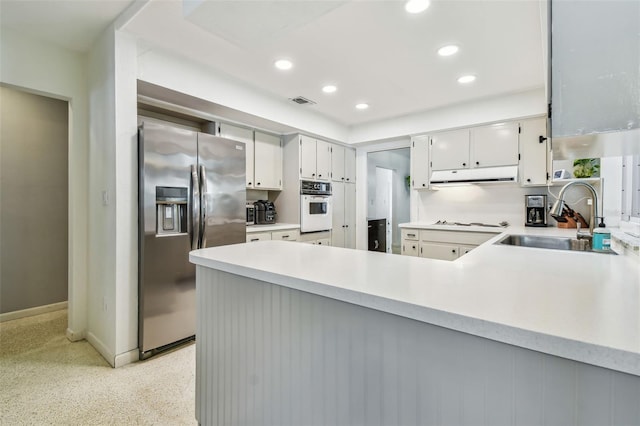 kitchen with sink, white cabinets, stainless steel fridge, kitchen peninsula, and white gas cooktop