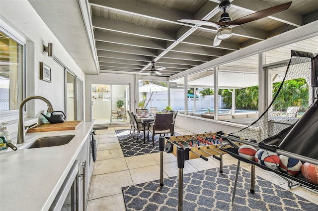 sunroom with beamed ceiling, sink, and ceiling fan